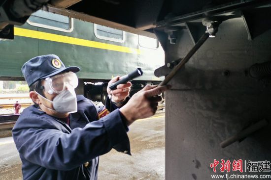 2.發電車乘務員在列車整備庫內，敲擊檢查車下電池箱固定螺栓，保證緊固安全。王玉星 攝